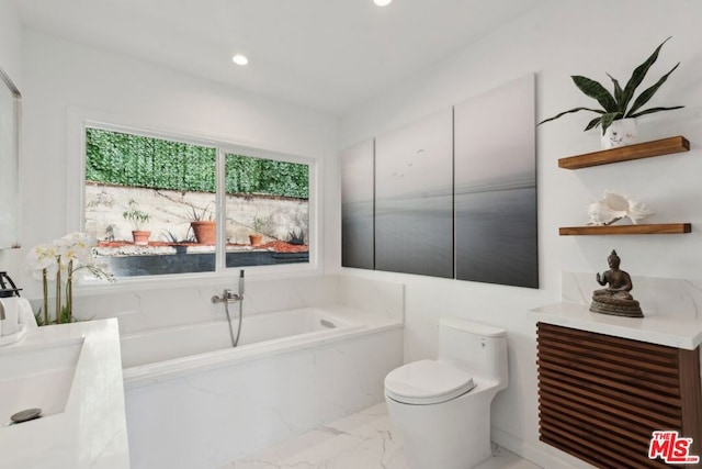 bathroom with toilet, vanity, and tiled tub