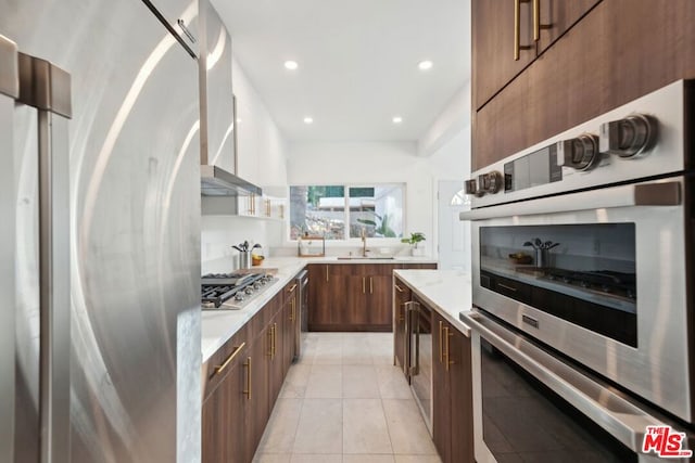 kitchen featuring sink, stainless steel appliances, wall chimney exhaust hood, and light tile patterned flooring