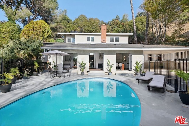 back of house with a fenced in pool and a patio