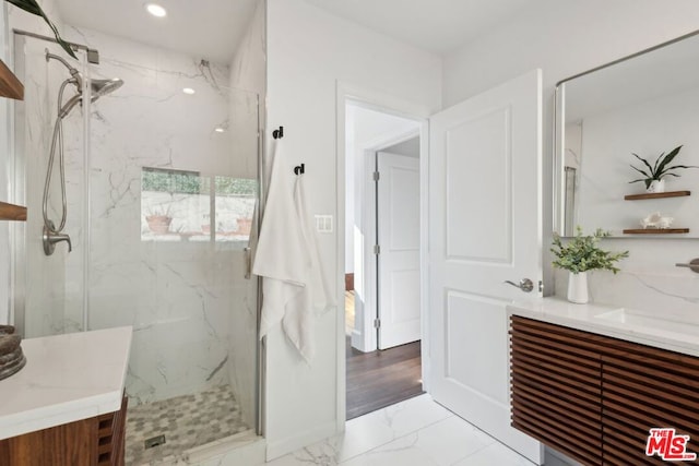 bathroom featuring a shower with shower door and vanity