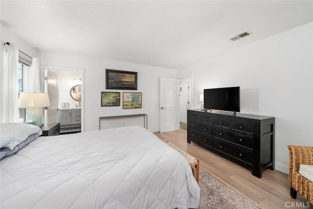 bedroom featuring ensuite bathroom and light hardwood / wood-style flooring