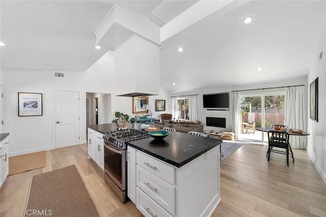 kitchen with gas range, light wood-type flooring, a center island, and white cabinetry