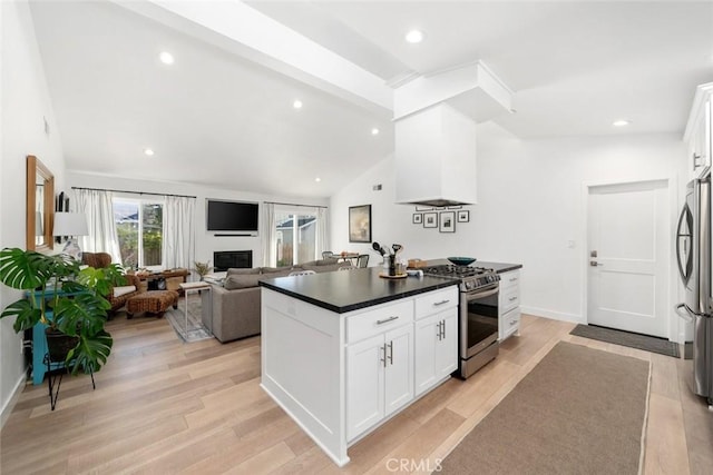 kitchen featuring appliances with stainless steel finishes, light wood-type flooring, premium range hood, white cabinets, and vaulted ceiling with beams