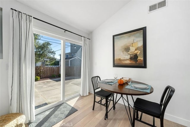 dining space featuring vaulted ceiling and light wood-type flooring