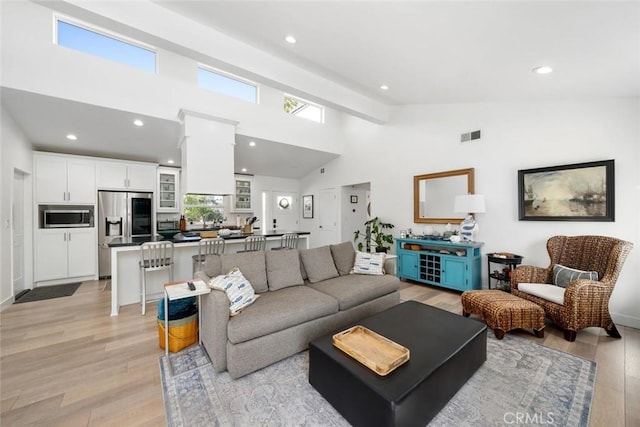 living room featuring light hardwood / wood-style flooring and high vaulted ceiling