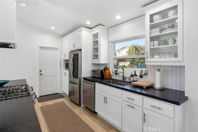 kitchen featuring decorative backsplash, light wood-type flooring, stainless steel appliances, sink, and white cabinetry