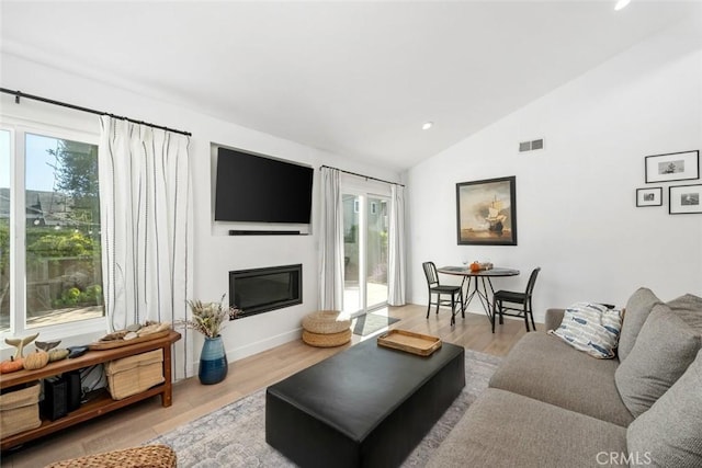 living room with light wood-type flooring, a wealth of natural light, and lofted ceiling