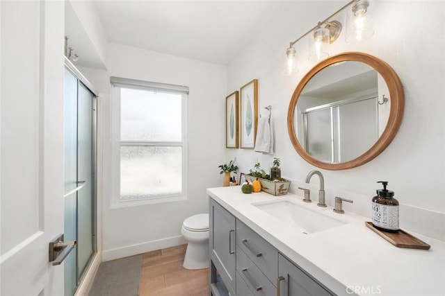 bathroom featuring hardwood / wood-style floors, vanity, toilet, and a shower with door