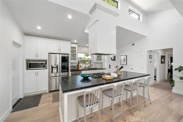 kitchen featuring a breakfast bar area, white cabinetry, light wood-type flooring, and appliances with stainless steel finishes