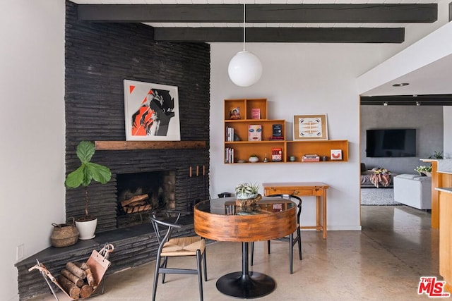 dining room with beam ceiling, concrete flooring, and a fireplace