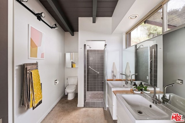 bathroom featuring toilet, beamed ceiling, tiled shower, vanity, and tile patterned flooring