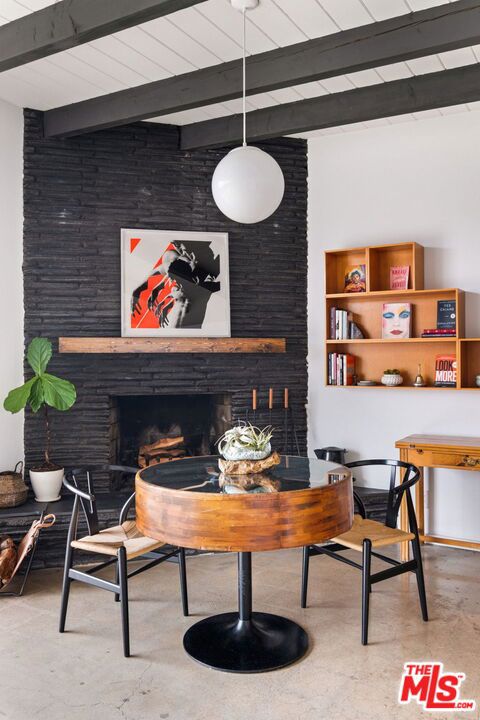 interior space with beam ceiling, concrete flooring, and a brick fireplace