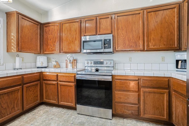 kitchen with tile countertops, lofted ceiling, and appliances with stainless steel finishes