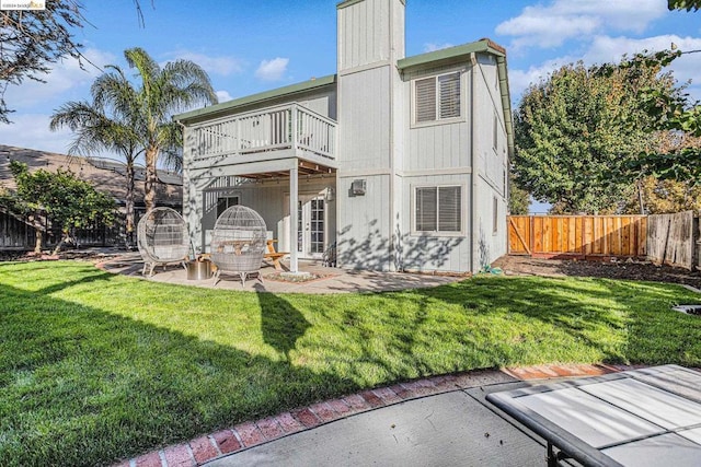 rear view of property with a patio, a balcony, and a lawn