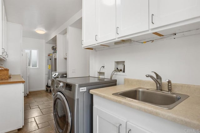 washroom featuring cabinets, independent washer and dryer, electric water heater, and sink