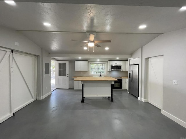 kitchen featuring white cabinetry, a kitchen bar, butcher block countertops, appliances with stainless steel finishes, and a kitchen island