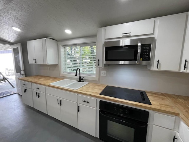 kitchen featuring a textured ceiling, white cabinets, black appliances, wooden counters, and sink