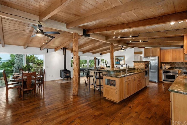 kitchen featuring appliances with stainless steel finishes, decorative backsplash, a wood stove, wooden ceiling, and a breakfast bar area