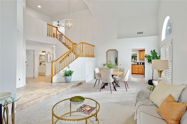 carpeted living room with a towering ceiling and an inviting chandelier