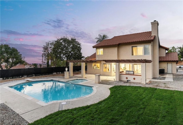 back house at dusk featuring a pool with hot tub, central AC unit, a lawn, and a pergola