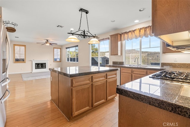 kitchen featuring ceiling fan, a center island, sink, light hardwood / wood-style flooring, and decorative light fixtures