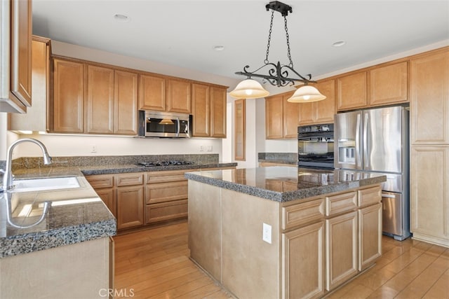 kitchen featuring sink, light hardwood / wood-style floors, decorative light fixtures, a kitchen island, and appliances with stainless steel finishes