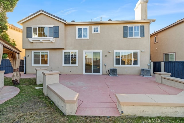 back of property with central air condition unit, a patio area, and a gazebo