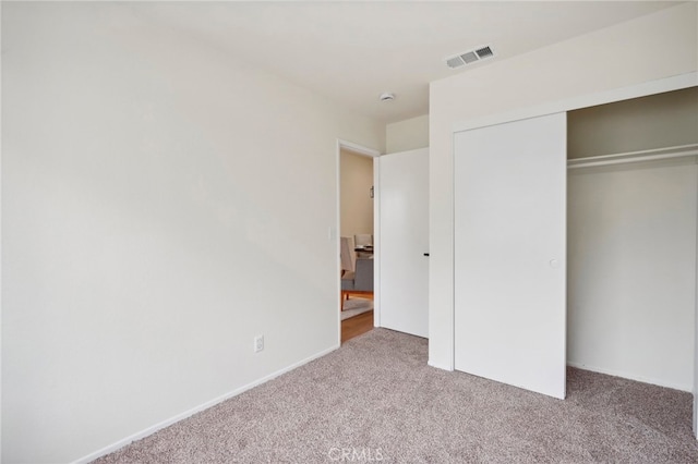 unfurnished bedroom with a closet and light colored carpet