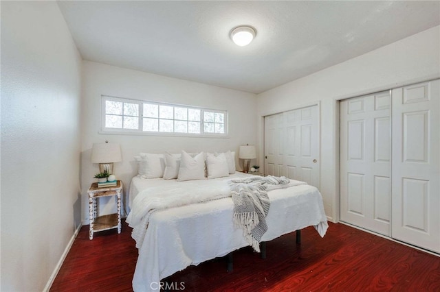 bedroom with multiple closets and dark wood-type flooring