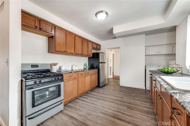 kitchen with gas range, electric range oven, light hardwood / wood-style flooring, stainless steel fridge, and sink