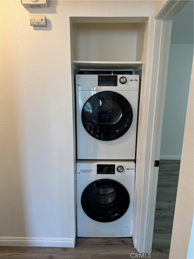 laundry room featuring dark hardwood / wood-style flooring and stacked washing maching and dryer