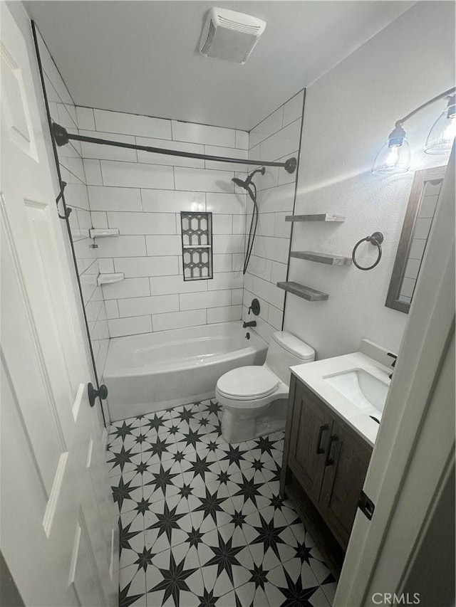 full bathroom featuring vanity, tiled shower / bath combo, and toilet