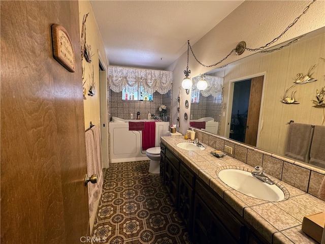 bathroom with vanity, toilet, a textured ceiling, and a washtub