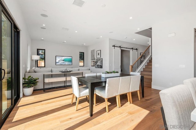 dining room featuring a barn door and light hardwood / wood-style floors