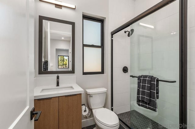 bathroom featuring toilet, vanity, and a shower with door