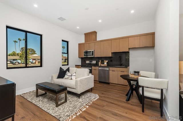 kitchen with backsplash, hardwood / wood-style floors, sink, stainless steel appliances, and light brown cabinetry