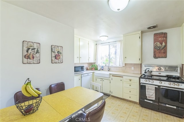 kitchen featuring tasteful backsplash, white cabinetry, white dishwasher, black range, and sink