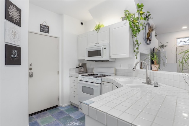 kitchen featuring white appliances, sink, tile countertops, kitchen peninsula, and white cabinets