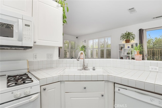 kitchen featuring white cabinets, kitchen peninsula, tile counters, and white appliances