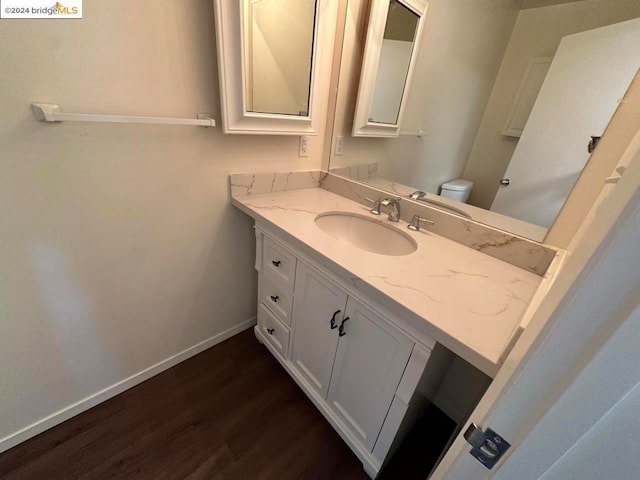 bathroom featuring vanity, hardwood / wood-style flooring, and toilet