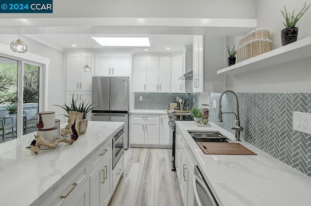 kitchen with white cabinetry, stainless steel appliances, light stone countertops, and pendant lighting