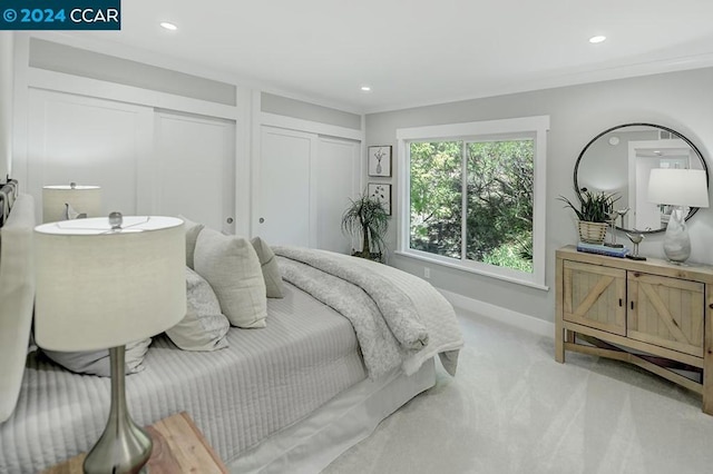 bedroom featuring light carpet and two closets