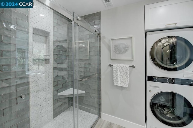 bathroom with stacked washing maching and dryer, hardwood / wood-style flooring, and walk in shower