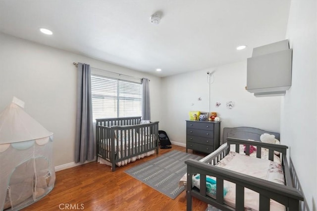 bedroom featuring dark wood-type flooring and a nursery area