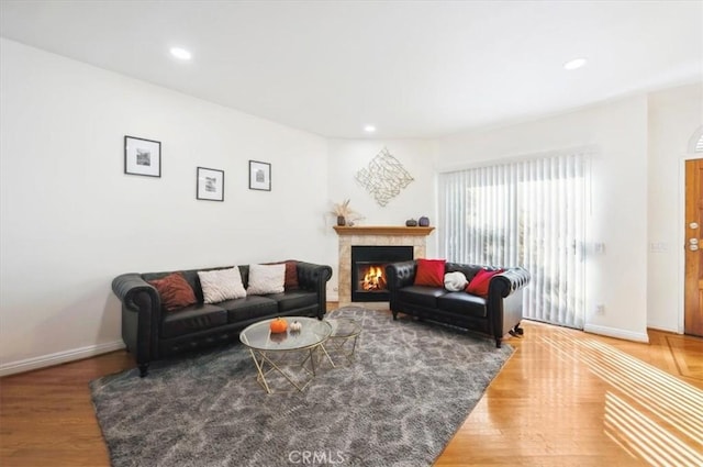 living room with wood-type flooring and a tiled fireplace