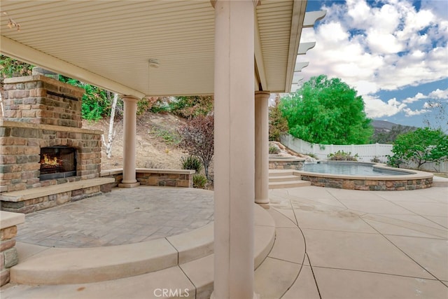 view of patio / terrace with a hot tub, a mountain view, and an outdoor stone fireplace