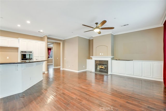 unfurnished living room with crown molding, hardwood / wood-style floors, a fireplace, and ceiling fan