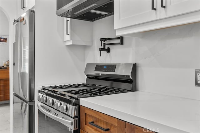 kitchen featuring range hood, white cabinets, and appliances with stainless steel finishes