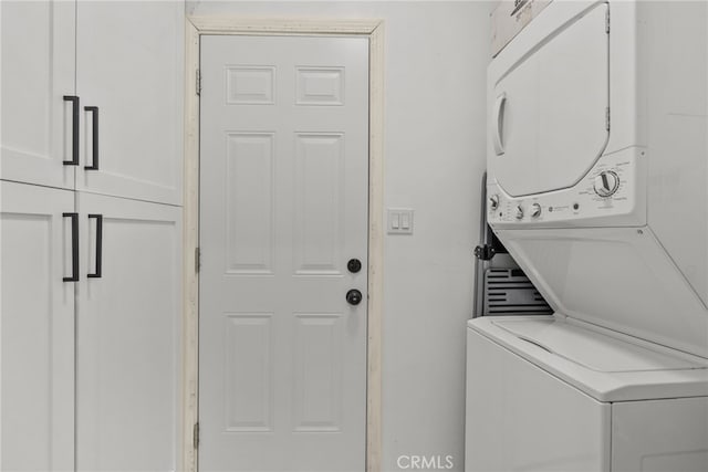 laundry room with cabinets and stacked washer and clothes dryer