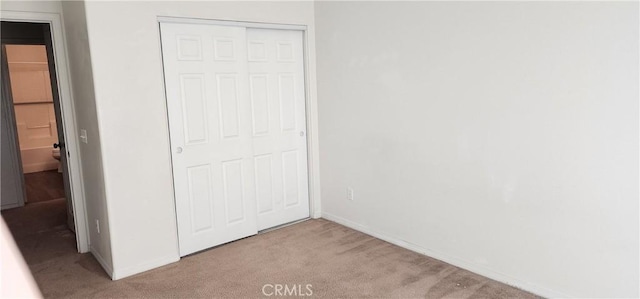 unfurnished bedroom with light carpet and a closet